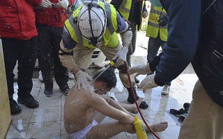 Syrian Civil Defense members spray water on a rebel fighter, affected by what activists said was a gas attack in Idlib city, March 31, 2015. [photo by Abed Kontar/Reuters]